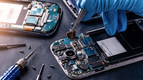 Technician repairing an Android phone, carefully replacing internal components.
